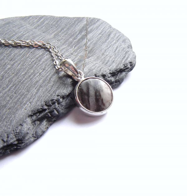 Banded British Stone Pendant. A men's or women's pendant in white and black striped stone, handcrafted into a cabochon and set in a round, sterling silver pendant. The gemstone in this pendant is British gneiss, collected in Northumbria, England, and most likely originating in Lewis off the west coast of Scotland. Natural British gemstone pendant by Northumbria Gems.