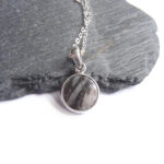 Black & White Banded British Stone Pendant. A men's or women's pendant in white and black striped stone, handcrafted into a cabochon and set in a round, sterling silver pendant. The gemstone in this pendant is British gneiss, collected in Northumbria, England, and most likely originating in Lewis off the west coast of Scotland. Natural British gemstone pendant by Northumbria Gems.