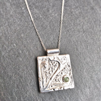 Coastal Inspired Natural Apatite Silver Pendant. Large square silver pendant with a textured surface design, inspired by beach pebbles and seaweed fronds from the Northumbrian coast. Set with a tiny piece of apatite gemstone from a beach in Northumbria.