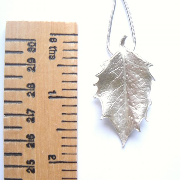 Large silver holly leaf necklace, handcrafted in ethical silver with fine detail from a real holly leaf. Made in England. Next to a ruler to show the size.