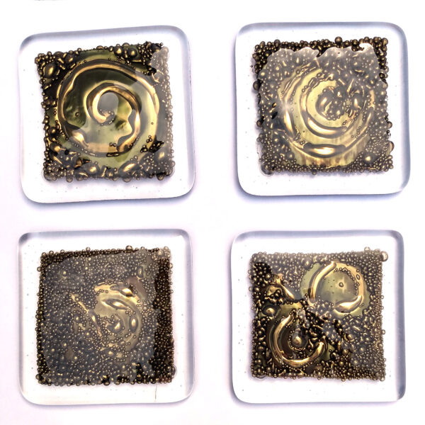 Set of 4 Rock Art Fused Glass Coasters. Small ornamental coasters individually handcrafted and fused in a kiln. Four clear glass coasters with a textured metallic effect design. The spiral and curved shapes are inspired by prehistoric rock carvings, or cup and ring marks, seen on my walks in the lovely county of Northumberland. Made in England.