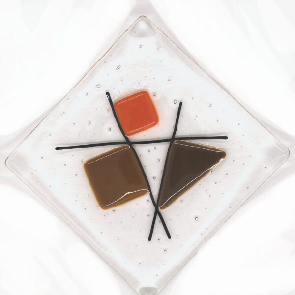 Geometric glass dish tan and orange on clear. A sixties retro dish with tan, brown and orange shapes intersected with black lines. Handcrafted using fused glass techniques. Made in England.